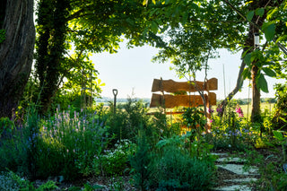 Wooden swing set in a lush garden with trees and plants