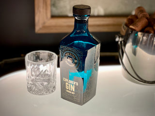 Bottle of 'Explorer's Gin' on a table with a glass and decorative items in the background.