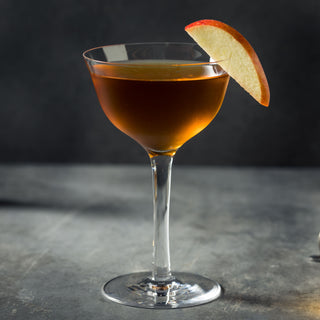 Cocktail in a glass with an apple slice on a dark background