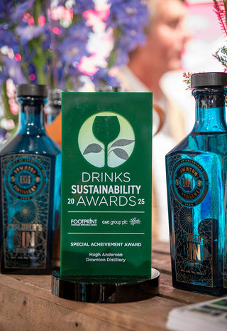 Green award plaque for Drinks Sustainability Awards 2025 with blue bottles in the background