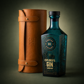A bottle of Downton Distillery Explorer's Gin London Dry stands next to its brown leather cylindrical carrying case on a dark gradient background.