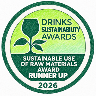 A circular award badge for the Drinks Sustainability Awards, 2026, highlighting the Sustainable Use of Raw Materials Award Runner Up. The badge features a green and white design with a hand-drawn sketch style, showing a wine glass silhouette and a plant sprig.
