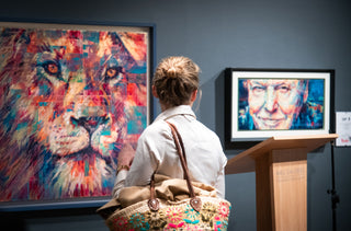 Woman looking at a painting of a lion and a portrait on a screen in an art gallery.