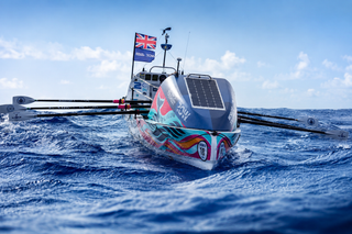 Solar-powered boat with solar panel on the deck, rowing through the ocean.