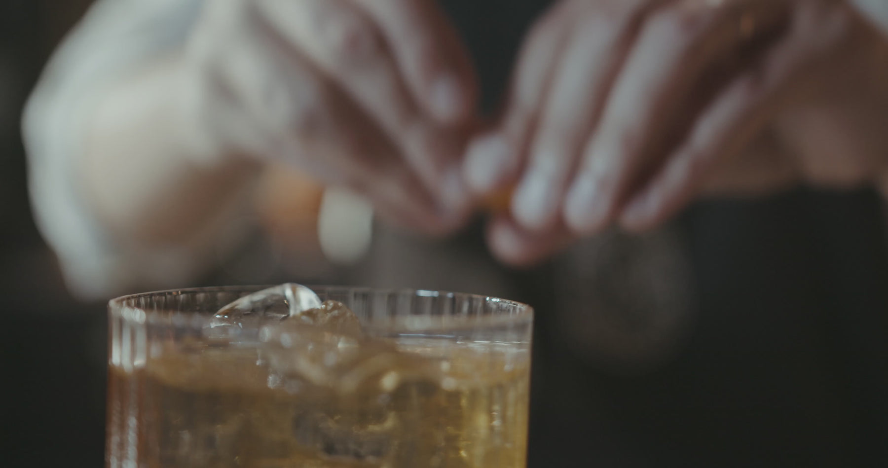 Man adding orange twist to a cocktail